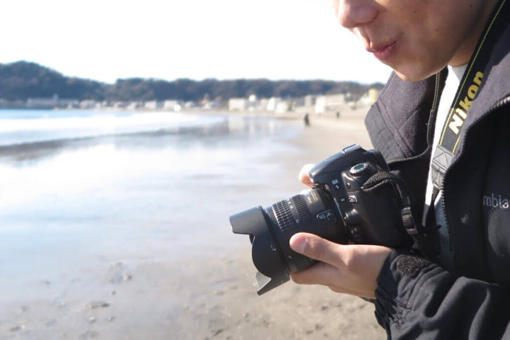 海辺で一眼レフカメラを持つ人