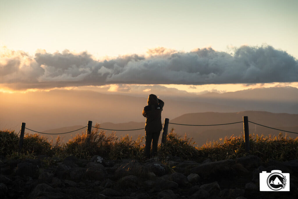 夕暮れ時の山の景色を望む人